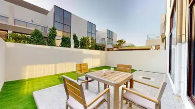 an outdoor patio with a wooden table and chairs at Locations l Spectacular 4 Bed Villa l Garden l Wadi Al Safa in Dubai