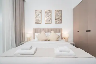 a white bedroom with a large white bed with two lamps at Vacay Lettings - Missoni Luxury 2 BR Urban Oasis Dubai Canal View in Dubai