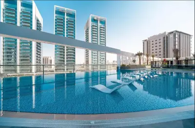 a large swimming pool in a city with tall buildings at Stunning New Studio - Near Dubai Hills Mall in Dubai