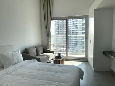 a bedroom with a bed and a couch and a window at Stunning New Studio - Near Dubai Hills Mall in Dubai