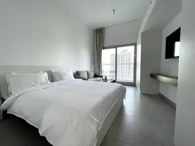 a white bedroom with a large bed and a couch at Stunning New Studio - Near Dubai Hills Mall in Dubai