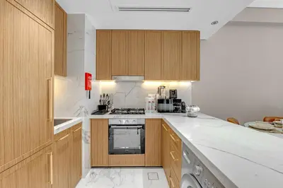 a kitchen with white marble counter tops and wooden cabinets at Charming 2BR Getaway at Azizi Riviera, MBR City in Dubai