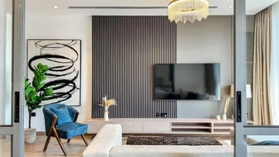 a living room with a television and a blue chair at 1BDR near Circle Mall with Sauna, Jaccuzzi and Gym in Dubai