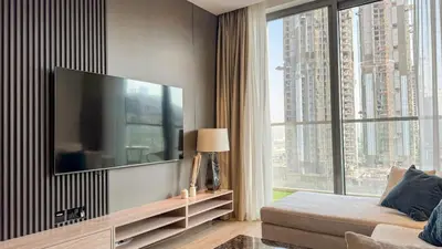 a living room with a large television and a large window at 1BDR near Circle Mall with Sauna, Jaccuzzi and Gym in Dubai