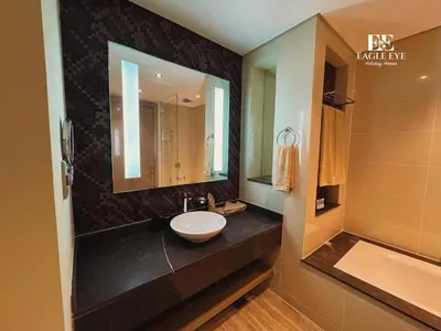 a bathroom with a sink and a mirror and a tub at EagleEye Paramount Tower D 1BR Sleeps 4 in Dubai
