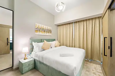 a bedroom with a large bed and a mirror at ALiving Elegant 1BR I Golf Gate, DAMAC Hills in Dubai