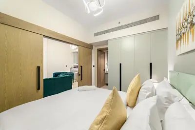 a bedroom with a large white bed with pillows at ALiving Elegant 1BR I Golf Gate, DAMAC Hills in Dubai