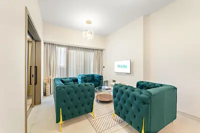 a living room with blue chairs and a table at ALiving Elegant 1BR I Golf Gate, DAMAC Hills in Dubai