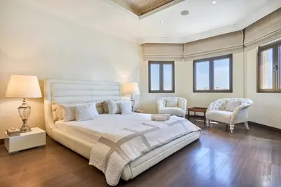 a bedroom with a large bed and two chairs at JuliusHomes-Villa Noor in Dubai