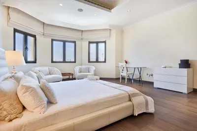a white bedroom with a large bed and a table at JuliusHomes-Villa Noor in Dubai