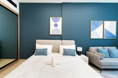 a blue bedroom with a large bed and a couch at HAVN - Modern Studio in Dusk, Al Barsha in Dubai