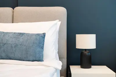 a bed with a black lamp on a side table at HAVN - Modern Studio in Dusk, Al Barsha in Dubai