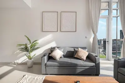 a living room with a gray couch and a window at Deluxe Nine Tower Suites By Hostiva - Downtown in Dubai