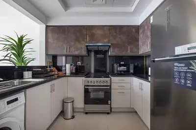 a kitchen with white cabinets and a stove top oven at Deluxe Nine Tower Suites By Hostiva - Downtown in Dubai