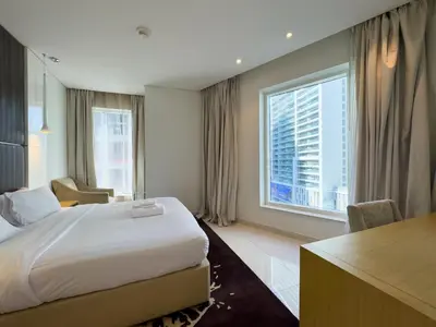 a hotel room with a bed and a desk and window at Werova - Spacious 3-Bedroom Near Dubai Mall in Dubai