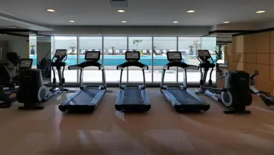 a gym with a row of treadmills and a pool at Werova - Spacious 3-Bedroom Near Dubai Mall in Dubai