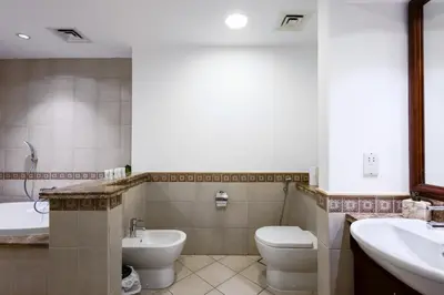 a bathroom with a toilet and a tub and a sink at Spacious 1BR with Terrace l Near Palm Jumeirah Mall in Dubai