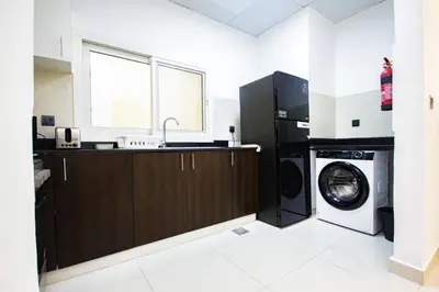 a kitchen with a washing machine and a sink at Dezire Premium Fully Furnished 1 BHK Apartment in Dubai