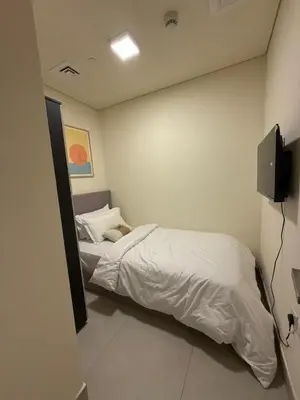 a small bedroom with a bed and a television at Joyful Journeys Marina Arcade Private Room for 2 - Shared Kitchen in Dubai