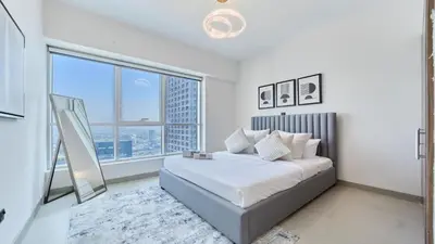a white bedroom with a bed and a large window at fam Living High Floor Stay in Sulafa Tower in Dubai