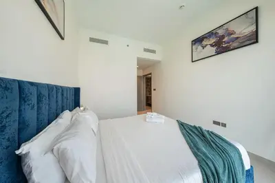 a bedroom with a white bed with a blue headboard at Stunning Full Burj Khalifa and Fountain View Apartment in Dubai