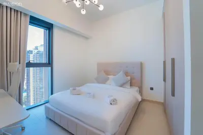 a white bedroom with a large white bed and a window at Burj Khalifa - Fountain View - Astonishing Home in Dubai