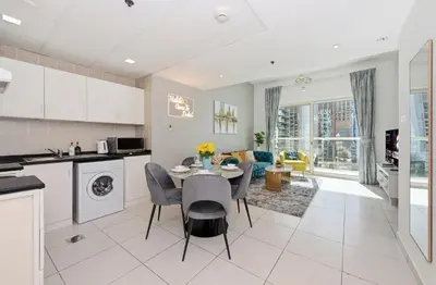 a kitchen and living room with a table and chairs at Vibrant 1 Bedroom Marina View - Stylish and Bright Stay in Dubai
