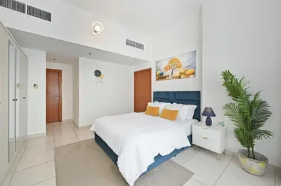 a white bedroom with a large bed and a plant at Vibrant 1 Bedroom Marina View - Stylish and Bright Stay in Dubai