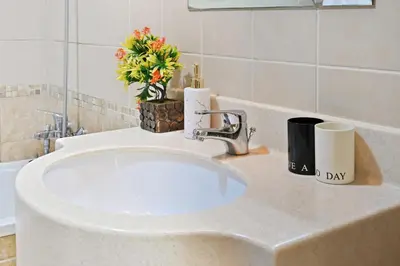 a bathroom counter with a white sink and a flower arrangement at Vibrant 1 Bedroom Marina View - Stylish and Bright Stay in Dubai