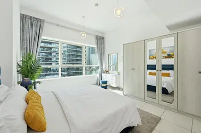 a bedroom with a large white bed and a window at Vibrant 1 Bedroom Marina View - Stylish and Bright Stay in Dubai