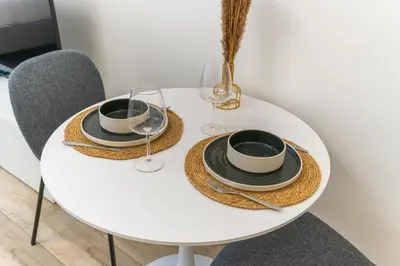 a white table with two plates and glasses on it at Modern studio - Burj & canal view in Dubai