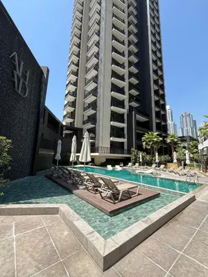 a swimming pool with lounge chairs and a tall building at Modern studio - Burj & canal view in Dubai
