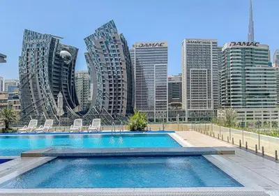 a swimming pool in front of a city with tall buildings at Luxurious apartment with Burj Khalifa & Canal Views in Dubai