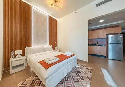a bedroom with a bed and a kitchen with a refrigerator at Luxurious apartment with Burj Khalifa & Canal Views in Dubai