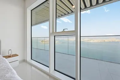 a bedroom with a large window overlooking the water at Luxury 2BR Emaar Beachfront with Private Beach & Infinity Pool, Palm Jumeirah & Atlantis Views in Dubai