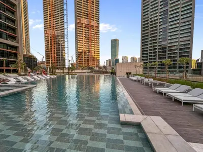 a pool with lounge chairs in a city with tall buildings at Artistic 2Bedroom with Skyline Khalifa View in Dubai