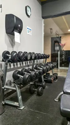 a rack of dumbbells in a gym with a clock at Stylish Dubai Stay in Dubai
