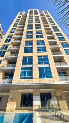 a tall building with a pool in front of it at Stylish Dubai Stay in Dubai