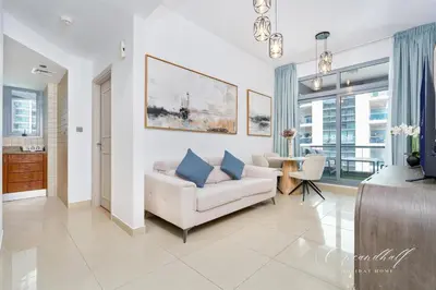 a living room with a white couch and blue pillows at Cool 1BR with Balcony in Marina, Steps from Metro in Dubai