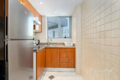 a kitchen with a stainless steel refrigerator and a sink at Cool 1BR with Balcony in Marina, Steps from Metro in Dubai