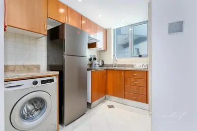 a kitchen with a refrigerator and a washing machine at Cool 1BR with Balcony in Marina, Steps from Metro in Dubai