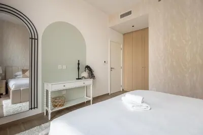 a white bedroom with a bed and a mirror at GuestReady - 1BR l Stylish 10th-Floor Retreat in Dubai