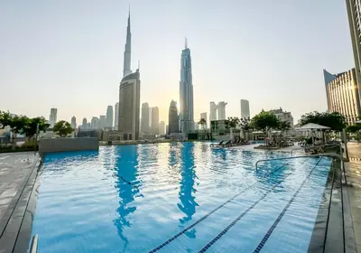a swimming pool with a city skyline in the background at Golden Stays - Stunning Downtown 2Br with Full Burj Views & Free Parking in Dubai