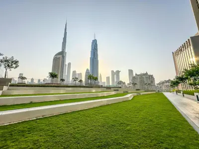 a park with grass and buildings in the background at Golden Stays - Stunning Downtown 2Br with Full Burj Views & Free Parking in Dubai