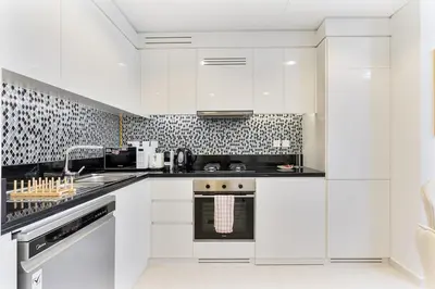 a white kitchen with black and white tiles at Modern 2Bed with Canal Views 7 Mins to Burj Khalifa in Dubai