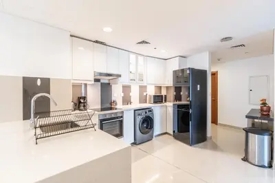 a kitchen with white cabinets and a washer and dryer at RH- Marina Living- Chic Ocean Heights 3BR with Panoramic Views in Dubai