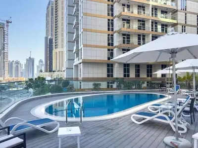 a swimming pool with chairs and umbrellas next to a building at Prime Downtown 3 BDR-2 mn to Dubai Mall in Dubai