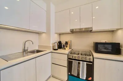 a kitchen with white cabinets and a stove and a sink at fam Living Chic 1BR Retreat in Dubai Hills Estate in Dubai