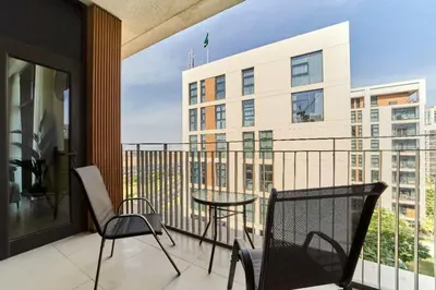 a balcony with chairs and a table and a building at fam Living Chic 1BR Retreat in Dubai Hills Estate in Dubai