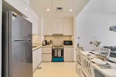 a kitchen with a refrigerator and a table with chairs at fam Living Chic 1BR Retreat in Dubai Hills Estate in Dubai